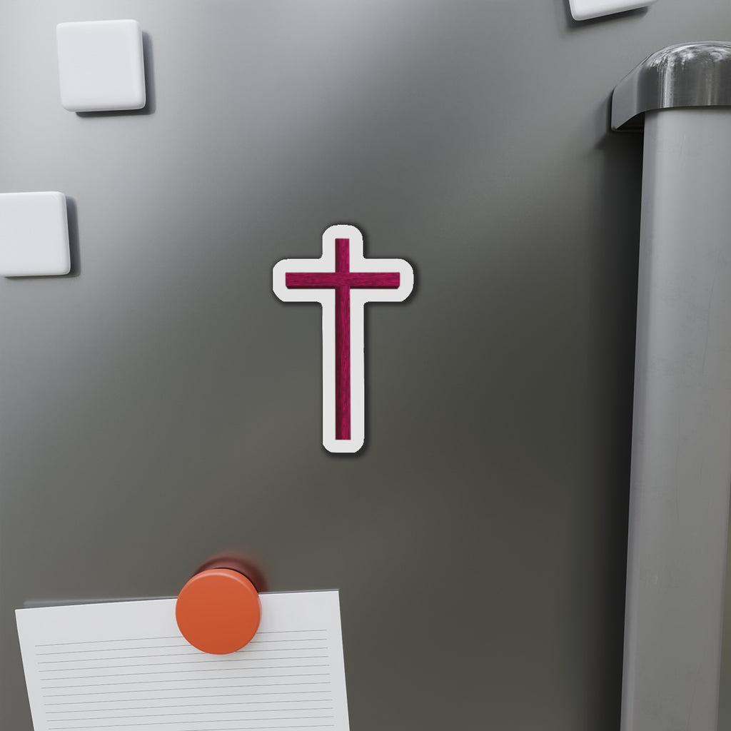 Cross-shaped magnet on a refrigerator door with a pen and paper attached.