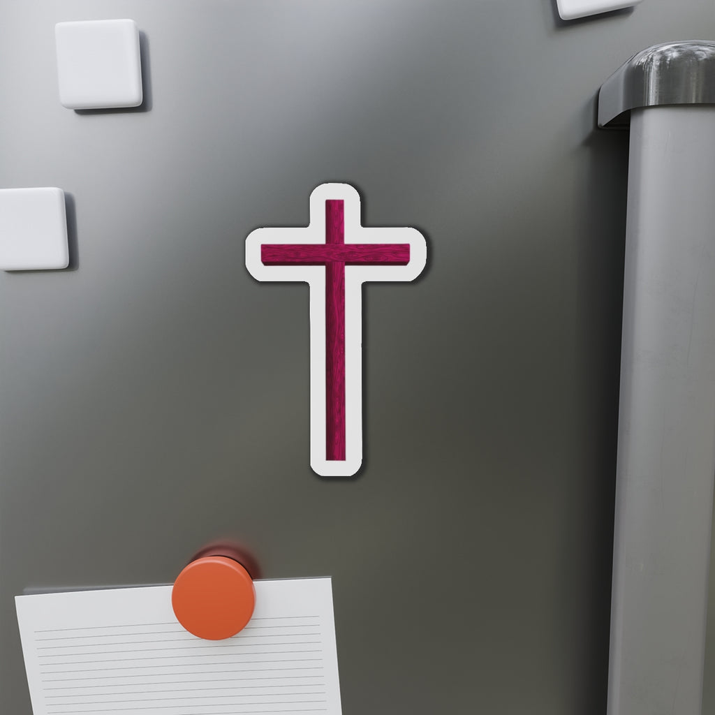 Cross-shaped magnet on a refrigerator door with a pen and paper attached.